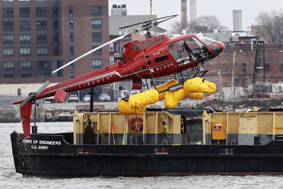 FILE - In this March 12, 2018 file photo, a helicopter, which crashed the previous day, is hoisted by crane from the East River onto a barge, in New York. The helicopter company, FlyNYON, exploited a regulatory loophole to avoid stricter safety requirements, federal investigators said Tuesday, Dec. 10, 2019. (AP Photo/Mark Lennihan, File)