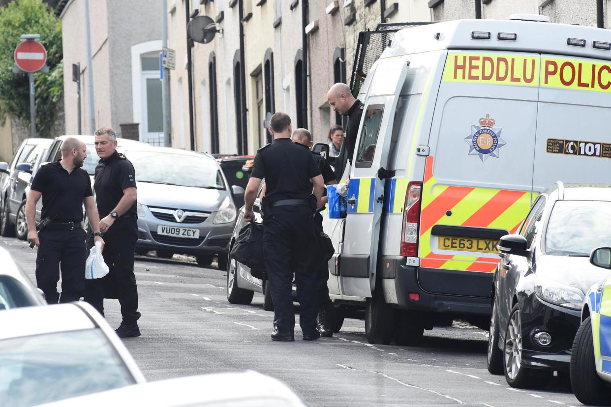 Police officers stand outside a Newport house being searched after three men were arrested in connection with an explosion on the London Underground: REUTERS