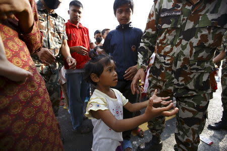 A girl spreading her arms asks soldiers for food near a makeshift shelter after the April 25 earthquake in Kathmandu May 9, 2015. REUTERS/Navesh Chitrakar