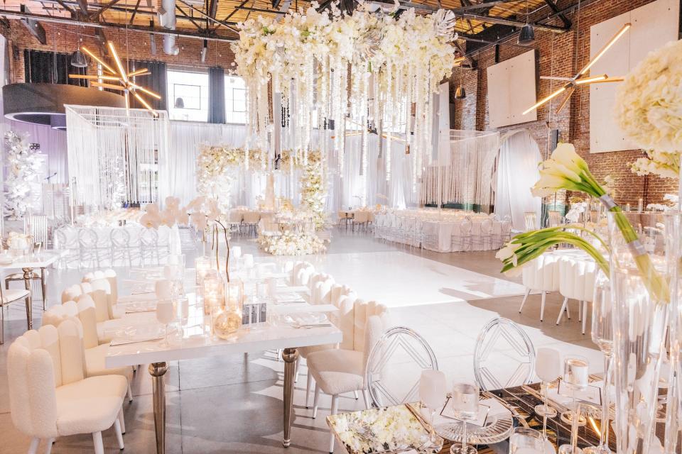 A wedding reception with white chairs, tables, and flowers.