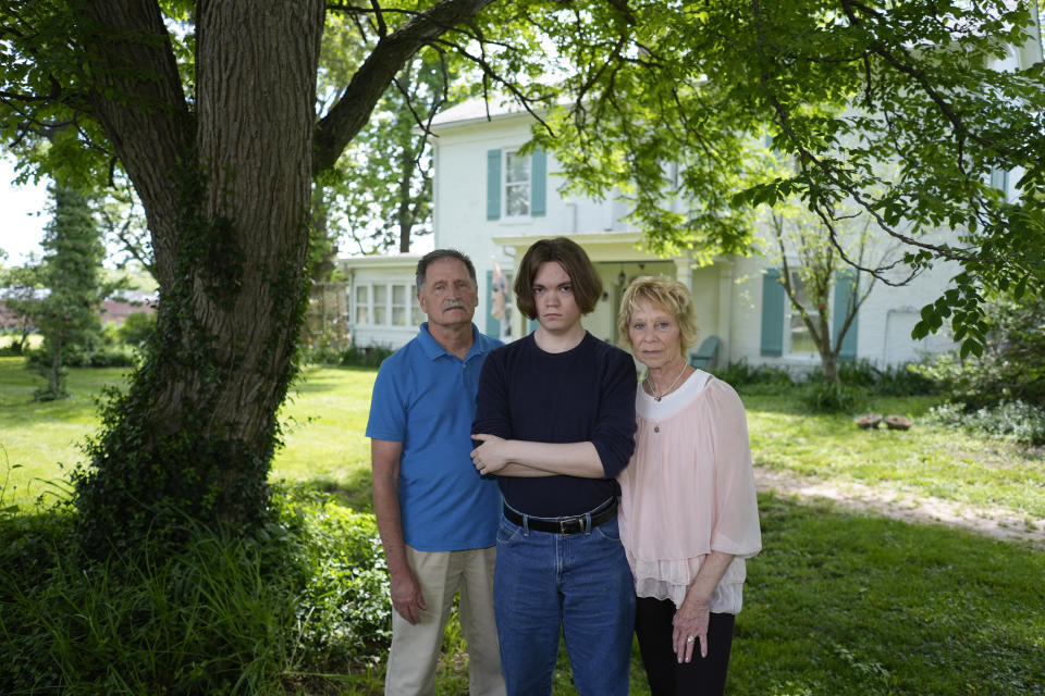 Jesse Fernandez, center, stands with his former foster parents Jason and Joyce White Friday, May 17, 2024, in Independence, Mo. Fernandez was paid thousands of dollars of Social Security survivor's benefits because of the death of his mother, but by the time he turned 18, the money had all been used by the state of Missouri and Fernandez's relatives to pay for his foster care. (AP Photo/Charlie Riedel)