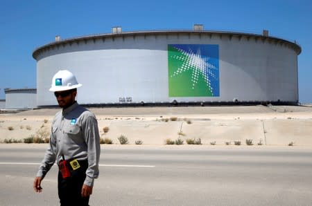 An Aramco employee walks near an oil tank at Saudi Aramco's Ras Tanura oil refinery and oil terminal