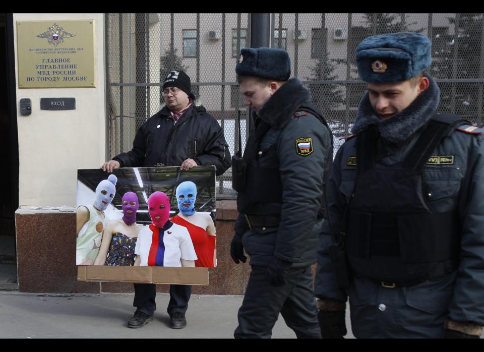 A supporter of a female Russian punk band holds a photo of the band while he and others picket the police headquarters in Moscow.