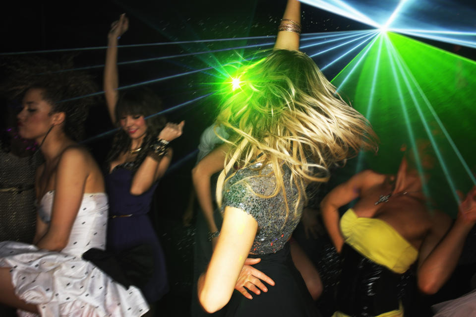 Group of young people dancing in nightclub with laser lighting.