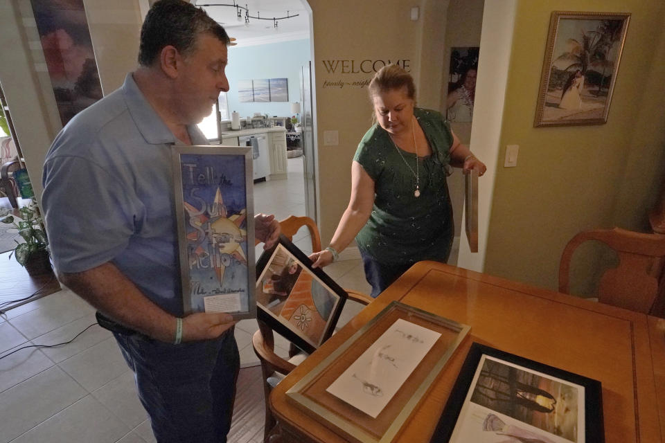 Tony and Jennifer Montalto show artwork made by their daughter, Gina Rose Montalto, at their dining room table during an interview, Friday, Feb. 3, 2023, in Parkland, Fla. Gina was one of the victims of Parkland's Marjory Stoneman Douglas High School shooting five years ago. Her parents set up the Gina Rose Montalto Memorial Foundation, to help dozens of college students and others. (AP Photo/Wilfredo Lee)