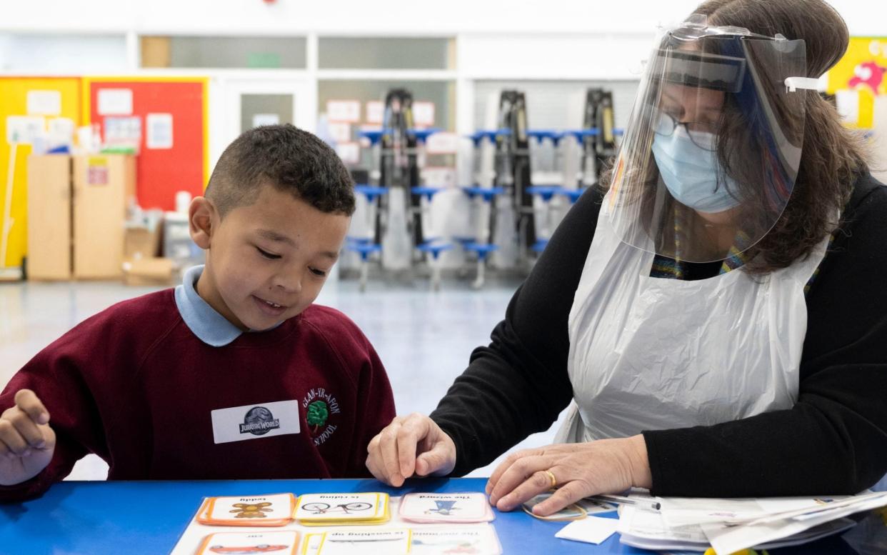 CARDIFF, WALES - MARCH 03: A child has a reading lesson with a teaching assistant wearing a face mask and visor at Glan-Yr-Afon primary school on March 3, 2021 in Cardiff, Wales. Children aged three to seven began a phased return to school in Wales from February 22. Wales education minister Kirsty Williams has said more primary school children will be able to return to face-to-face learning from March 15 if coronavirus cases continue to fall. - Matthew Horwood/Getty Images