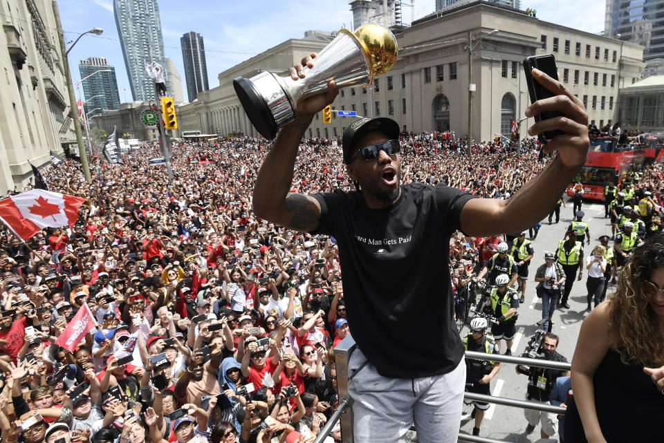 FILE - In this June 17, 2019, file photo, then Toronto Raptors forward Kawhi Leonard takes a photo while holding his playoffs MVP trophy during the NBA basketball championship team's victory parade in Toronto. The NBA's balance of power has shifted to the Los Angeles Clippers, who have never advanced beyond the second round let alone won a championship. All that is expected to change behind Leonard and Paul George, both regarded as two of the best two-way players in the league. (Frank Gunn/The Canadian Press via AP, File)