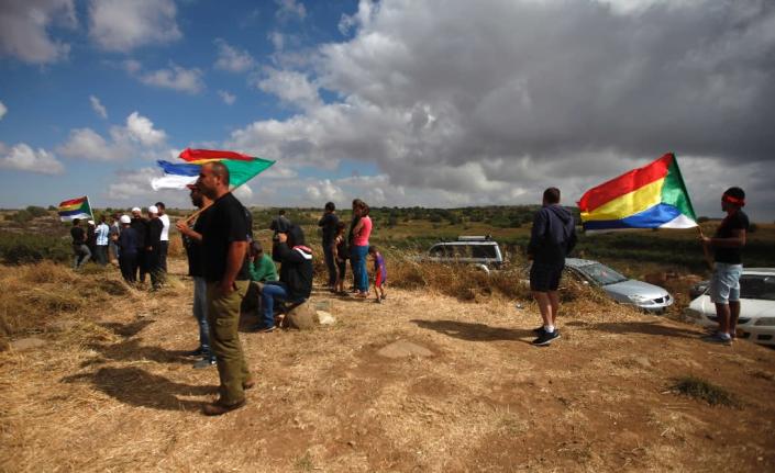 Druze men residing in Israel hold their community's flag and gather to watch smoke rise in the horizon of the Syrian Druze village of Hadar in Israeli-annexed Golan Heights on June 20, 2015 (AFP Photo/Jalaa Marey)