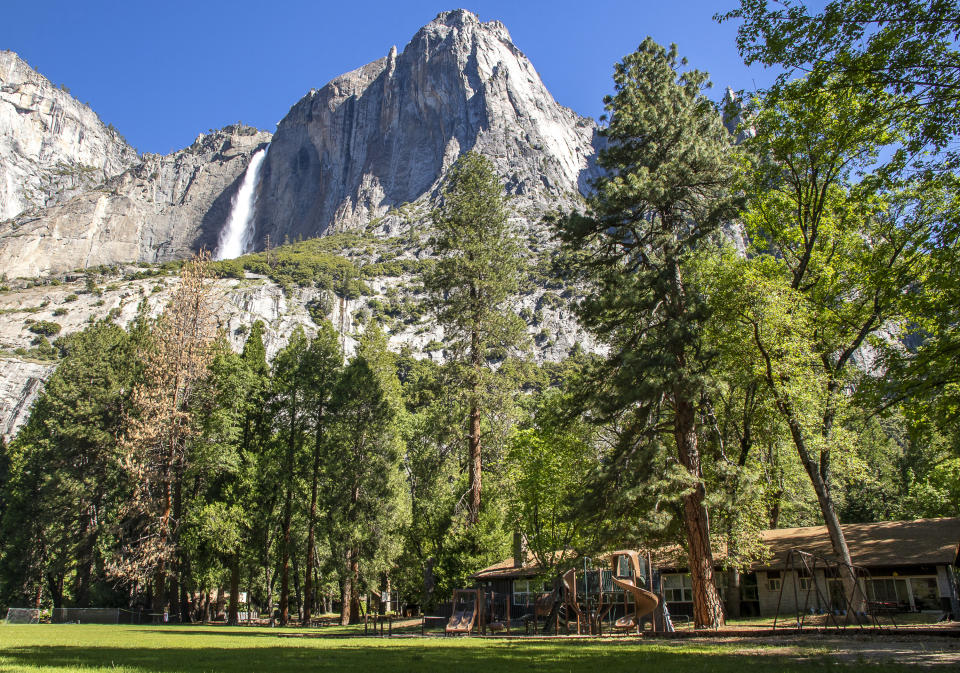 In this May 27, 2020, photo provided by the National Park Service, Yosemite Valley School, lower right, stands in Yosemite National Park, Calif. In the background is Upper Yosemite Falls. The school, the only one inside the 1,200-sq. mile (3,100-sq. kilometer) Yosemite park, shut its doors in mid-March due to the coronavirus pandemic like others across America and class has been convening online. But the pandemic hasn't stopped the presses on the school year's last edition of "The Yosemite Eye," a publication that has so charmed its community it boasts a circulation of nearly 5,000 copies. (Jamie Richards/National Park Service via AP)