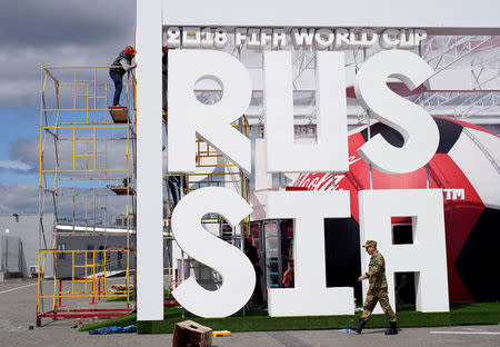 A worker puts his final touches to a booth while a solder walks past Kazan Arena, ahead of the start of the 2018 World Cup, in Kazan, Russia June 14, 2018. REUTERS/Toru Hanai