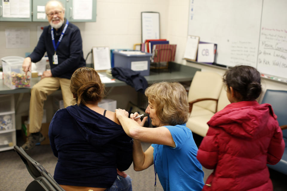 In in this Feb. 21, 2020 photo, volunteers give flu shots to newly arrived asylum seekers from Central America at Casa Alitas, a Catholic-run shelter in Tucson, Ariz., Friday. The previous year, throngs of asylum seekers streamed through Casa Alitas. Now it's often quiet because of tough new border policies and the coronavirus outbreak. (AP Photo/Dario Lopez-MIlls)