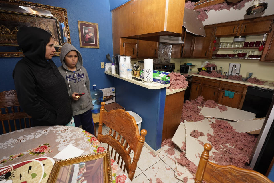 Maria Hernandez and her son, Alejandro Ambriz, 10, stand by the kitchen where the ceiling collapsed in their home, just one street east where an explosion occurred Friday, Jan. 24, 2020 in Houston. A massive explosion early Friday leveled a warehouse and damaged nearby buildings and homes, rousing frightened people from their sleep miles away. (Melissa Phillip/Houston Chronicle via AP)