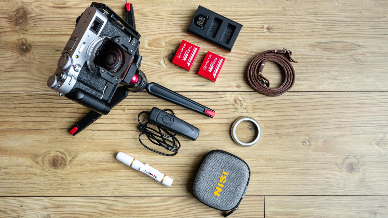  Fujifilm X100V and camera accessories on a wooden floor. 