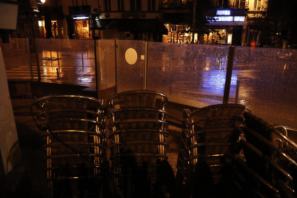 People eat in restaurants, background, across the road from a closed Irish pub in Brussels, Thursday, Oct. 8, 2020. Since bars in Brussels were forced to close as of Thursday for at least a month to deal with a massive surge in cases while restaurants were allowed to remain open, the big question on the streets is: when is a bar a bar and when is a bar a restaurant. (AP Photo/Francisco Seco)