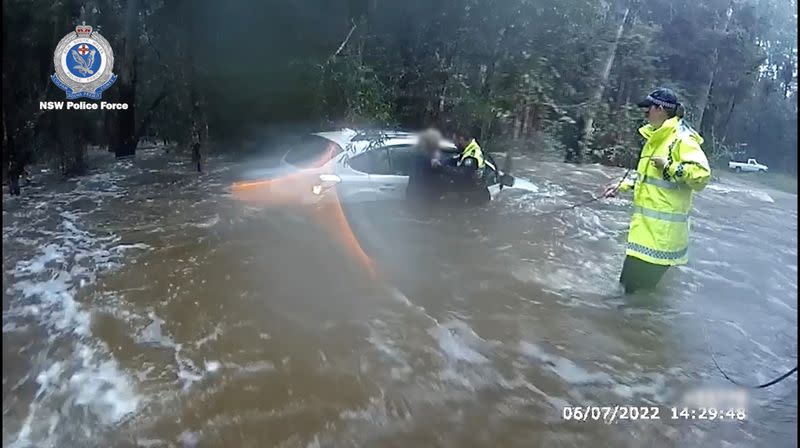 Police officers evacuate a woman from her flooded car in Collombatti, New South Wales