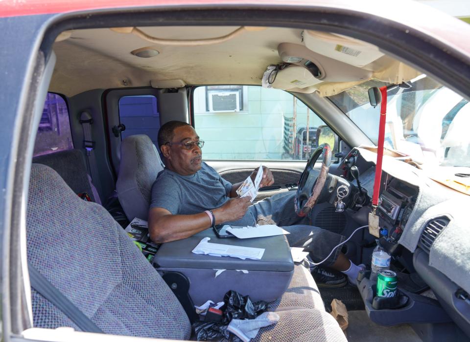 Ernest Benedict Holland, 64, leafs through bills while trying to stay cool inside his pickup after losing power at his home in Reserve, Louisiana, following Hurricane Ida.