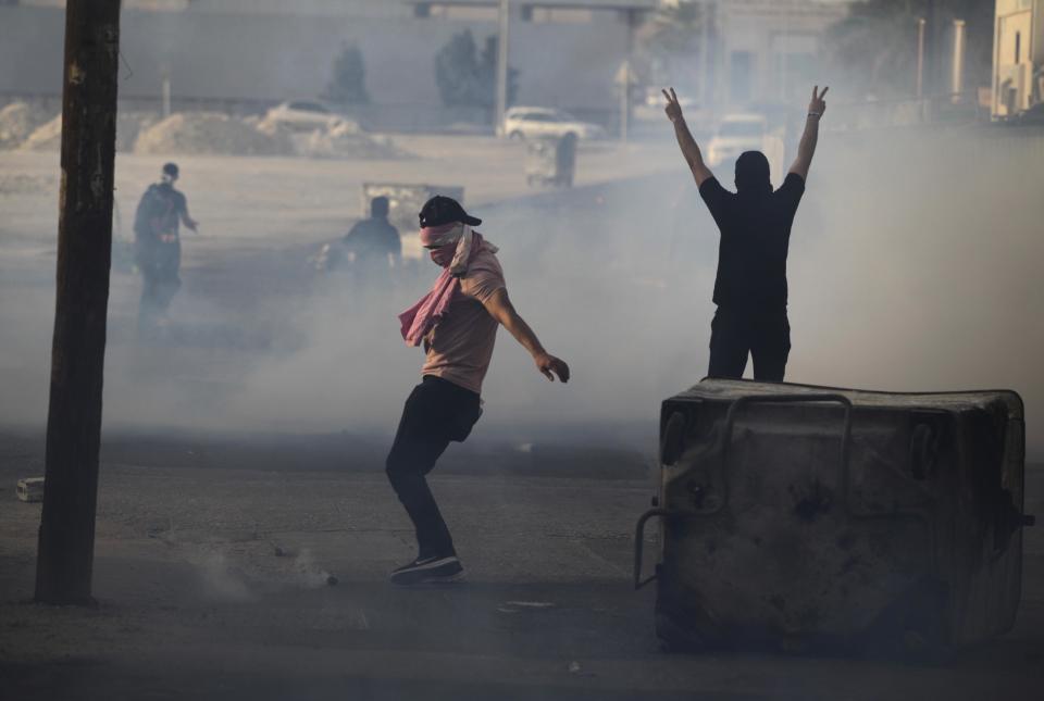 Bahraini anti-government protesters clash with riot police firing tear gas in Sanabis, Bahrain, on the edge of the capital of Manama, Saturday, April 19, 2014. Clashes erupted during a march in the village over a dispute between relatives and authorities about the official cause of death for a 27-year-old man who died Thursday of injuries sustained in earlier clashes. Authorities in Bahrain say an apparent car bombing has killed two people and wounded one west of the capital, Manama. (AP Photo/Hasan Jamali)