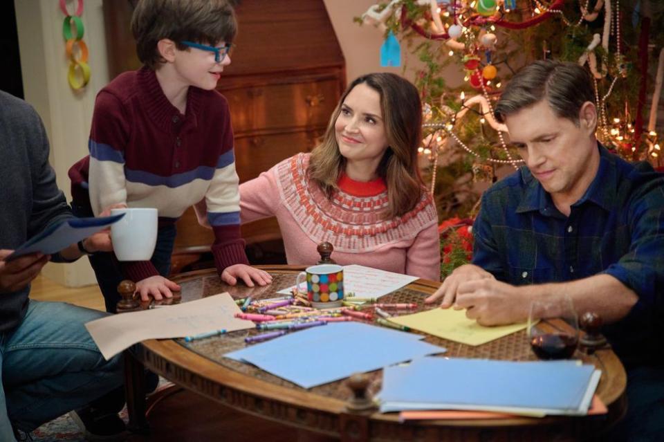 a group of people sitting around a table with a christmas tree