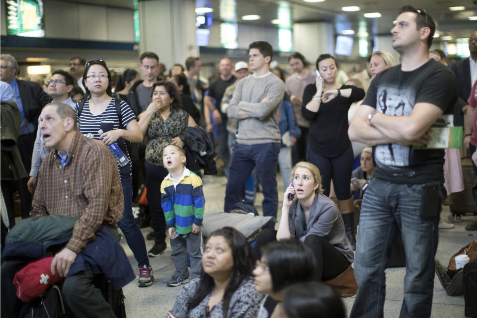 Evening rush hour commuters look at the departures board while at Penn Station, Friday, April 14, 2017, in New York. A New Jersey Transit train with about 1,200 passengers aboard is stuck in a Hudson River tunnel between New York and New Jersey. Authorities say the Northeast Corridor train became disabled Friday due to an Amtrak overhead power problem. (AP Photo/Mary Altaffer)