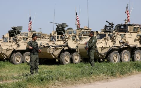 Kurdish fighters from the People's Protection Units (YPG) stand near U.S military vehicles in the town of Darbasiya - Credit: Reuters