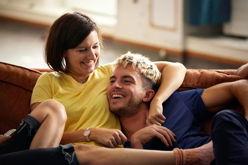 Louise Ford and Jonathan Bailey lay together on a couch