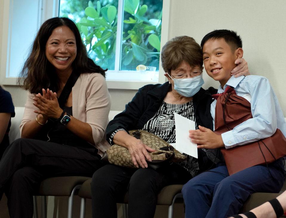 Emile Phanitnavong, 10, is congratulated by his grandmother, Margarite Adia, while his mother Trish Phanitnavong, applauds during the Palm Beach Fellowship of Christians and Jews' annual meeting Thursday in Palm Beach. Phanitnavong won the Special Judges award for his essay entry.