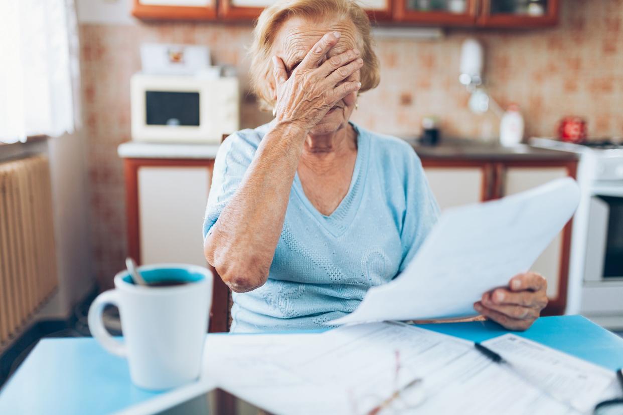 elderly woman looking at her utility bills while in the kitchen