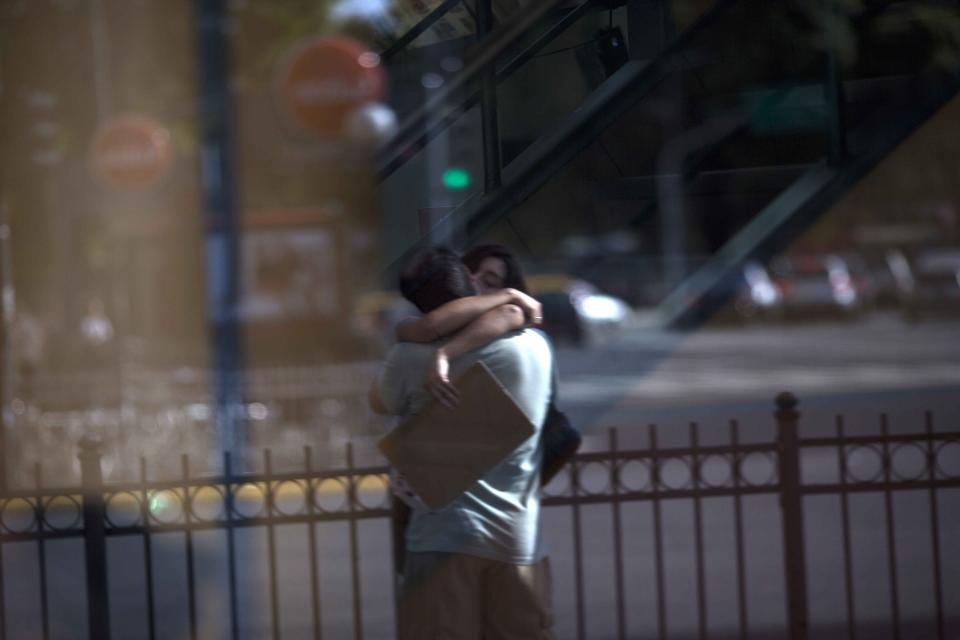 In this Feb. 4, 2014 photo taken through a window, a couple kisses in Buenos Aires, Argentina. Argentines have suffered through a tough summer, with tropical rain that provided no relief from the heat and humidity, people having to throw out rotten food because of rolling power blackouts and soaring oil and gas prices, all amid rising inflation that is making it ever harder to reach the end of the month. The strain is evident on the faces of subway riders and others making their way home in Buenos Aires, where signs of poverty and decay are ubiquitous just beyond the glamorous streets where tourists go. (AP Photo/Rodrigo Abd)