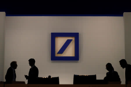 FILE PHOTO: People are silhouetted next to the Deutsche Bank's logo prior to the bank's annual meeting in Frankfurt, Germany, May 24, 2018. REUTERS/Kai Pfaffenbach