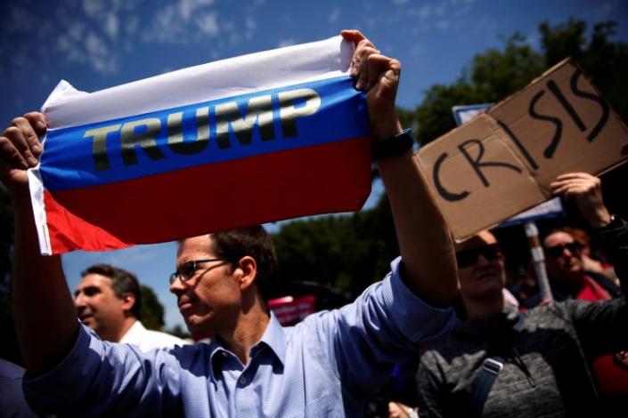 A protester holds a Russian flag with President Trump&#39;s name on it as demonstrators rally against Trump&#39;s firing of FBI Director James Comey, outside the White House