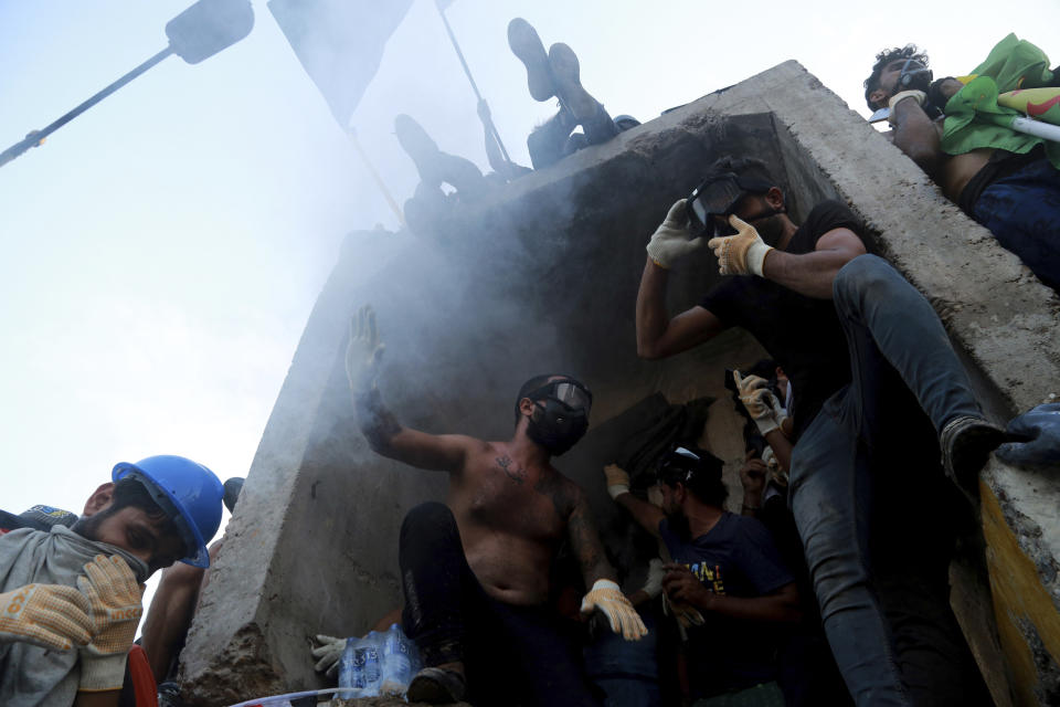 Anti-government protesters control the barriers while Iraqi security forces fire tear gas and close the bridge leading to the Green Zone, during a demonstration in Baghdad, Iraq, Tuesday, Oct. 29, 2019. (AP Photo/Hadi Mizban)