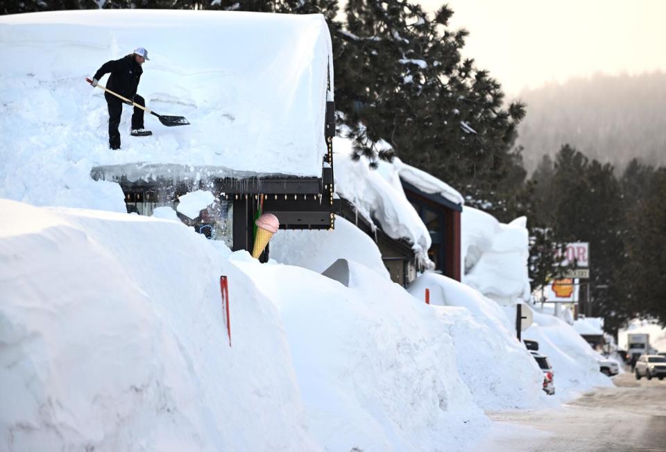 A person shovels snow from a roof.