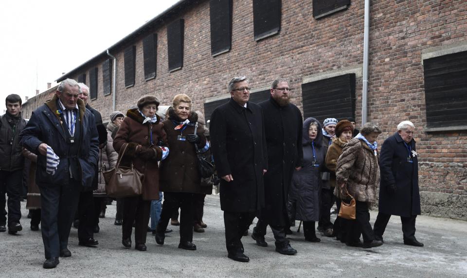 Polish President Bronislaw Komorowski (C), Piotr Cywinski (C-R), director of the Auschwitz-Birkenau museum and Auschwitz survivors arrive to lay down a wreath at the death wall of the former Auschwitz concentration camp on January 27, 2015 at the camp's memorial site in Oswiecim, Poland. Seventy years after the liberation of Auschwitz, ageing survivors and dignitaries gather at the site synonymous with the Holocaust to honour victims and sound the alarm over a fresh wave of anti-Semitism.     