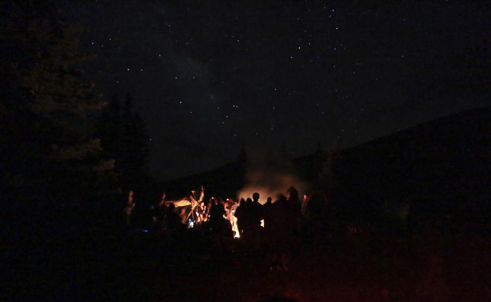 People drum and dance at a drum circle at the annual Rainbow Gathering on Friday, July 2, 2021, in the Carson National Forest, outside of Taos, N.M. More than 2,000 people have made the trek into the mountains of northern New Mexico as part of an annual counterculture gathering of the so-called Rainbow Family. While past congregations on national forest lands elsewhere have drawn as many as 20,000 people, this year’s festival appears to be more reserved. Members (AP Photo/Cedar Attanasio)