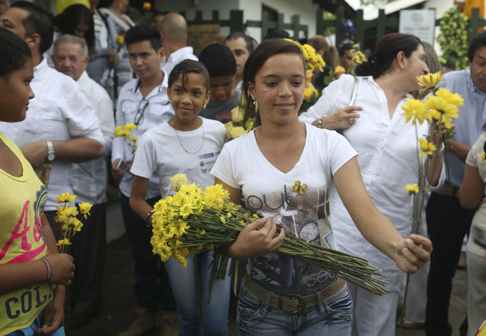 Youth hand flowers during a symbolic funeral ceremony for the late Colombian Nobel Literature laureate Gabriel Garcia Marquez in front of the house were he was born in Aracataca, in Colombia's Caribbean coast, Monday, April 21, 2014. Garcia Marquez died at the age of 87 in Mexico City on April 17, 2014. (AP Photo/Ricardo Mazalan)