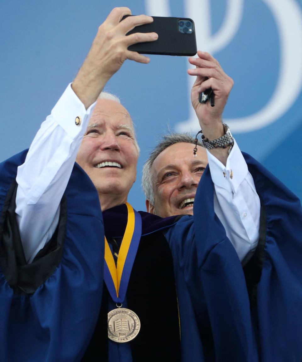 President Joe Biden (left) and University President Dennis Assanis take selfies - one with the crowd behind them, one the other direction - during the University of Delaware's 2022 Commencement at Delaware Stadium, Saturday, May 28, 2022.