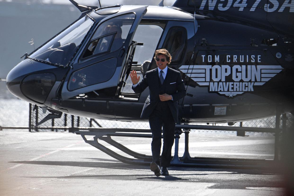 Tom Cruise step off a helicopter at the premiere of "Top Gun: Maverick" in a black suit