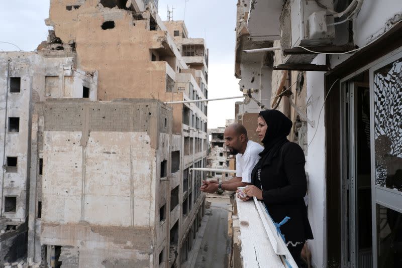 Nasia Abdullah Ali,36, and her brother Malik stand on a damaged balcony at home, in Benghazi