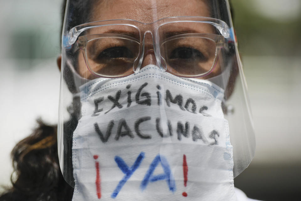 A healthcare worker, wearing a protective face mask with a message that reads in Spanish: "We demand vaccines now!", attends a march demanding a more equitable and faster distribution of COVID-19 vaccines, in the Los Palos Grandes neighborhood of Caracas, Venezuela, Saturday, April 17, 2021. (AP Photo/Matias Delacroix)