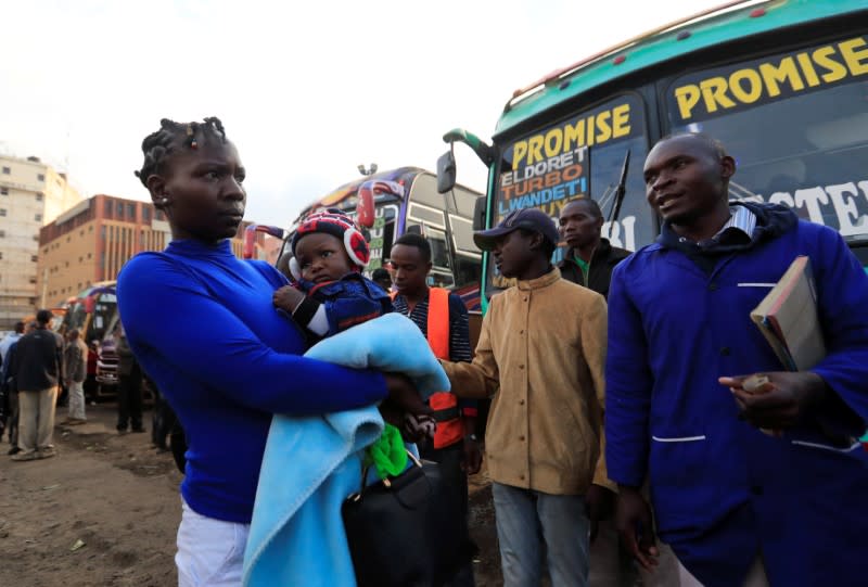 A passenger carries her child before boarding a disinfected public transport bus as residents leave for the villages amid concerns over the spread of coronavirus disease (COVID-19) in Nairobi