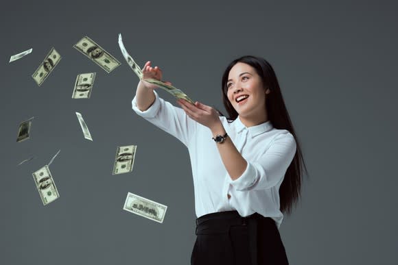 Well-dressed young woman flipping $100 bills off a stack.