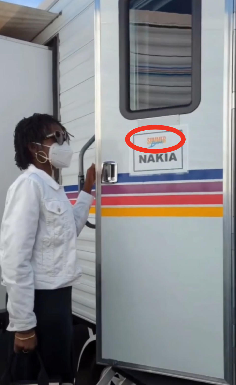 Lupita wearing a KN95 mask and opening the door of her trailer, and "Summer Break" on it circled