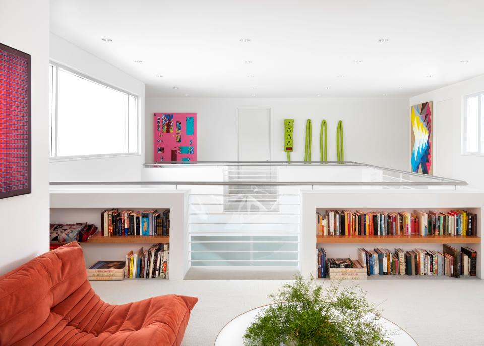 The open-air den on the second floor features seating by Ligne Roset and a vintage coffee table. The artwork is by Sara Cain (pink painting), Al Freeman (power cord soft sculpture), and Andrew Kuo.