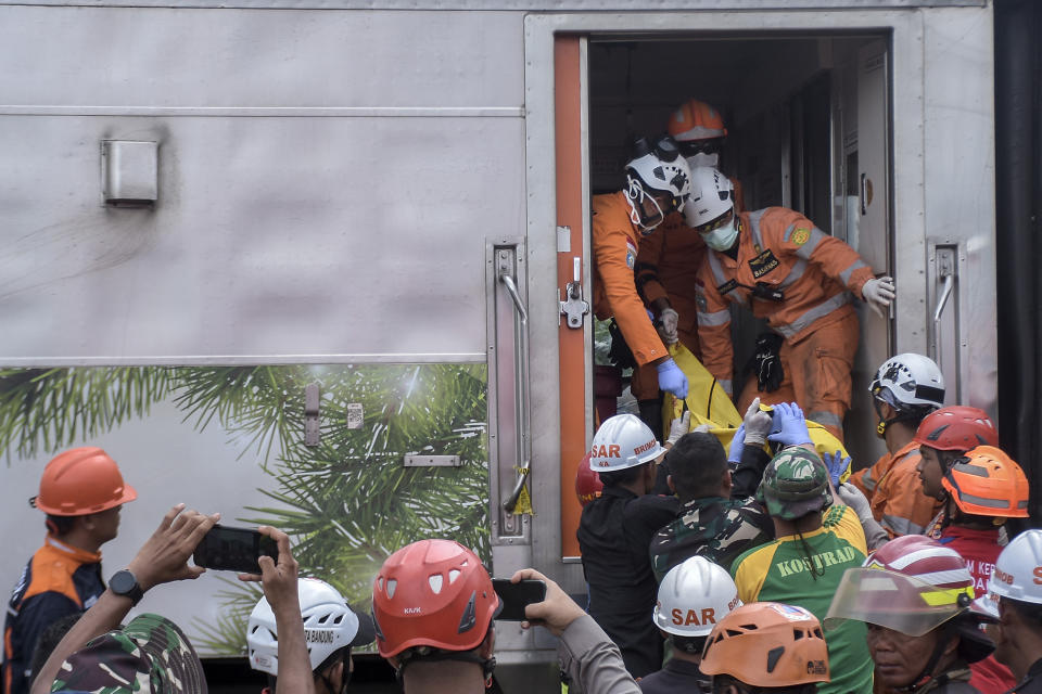 Rescuers remove the body of a victim after the collision between two trains in Cicalengka, West Java, Indonesia, Friday, Jan. 5, 2024. The trains collided on Indonesia's main island of Java on Friday, causing several carriages to buckle and overturn, officials said. (AP Photo/Abdan Syakura)