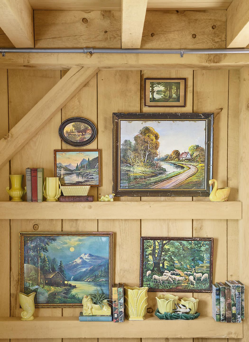 an exposed beam wall with landscape paintings and vases