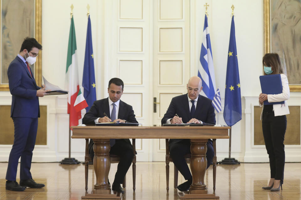 Greek Foreign Minister Nikos Dendias, right, and his Italian counterpart Luigi Di Maio asign an agreement following their meeting ,in Athens, on Tuesday, June 9, 2020. Greece will lift all restrictions on Italian tourists entering the country gradually between June 15 and the end of the month, Greece's foreign minister said Tuesday.(Costas Baltas /Pool via AP)