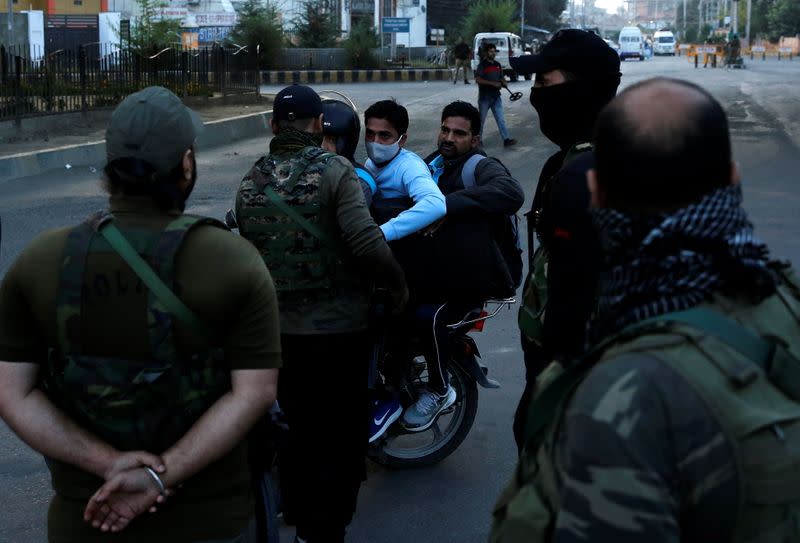 Indian security force personnel stop men riding a motorcycle at a barricade near the residence of Syed Ali Shah Geelani after his death in Srinagar