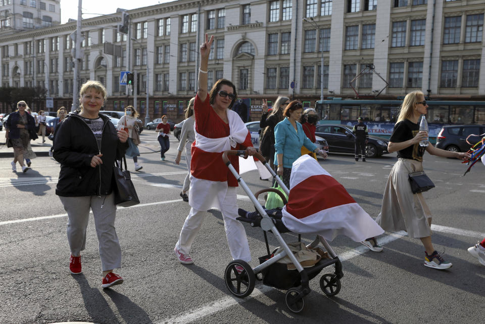 Women, one of them with an old Belarusian national flags, march during an opposition rally to protest the official presidential election results in Minsk, Belarus, Saturday, Sept. 12, 2020. Daily protests calling for the authoritarian president's resignation are now in their second month and opposition determination appears strong despite the detention of protest leaders. (AP Photo)