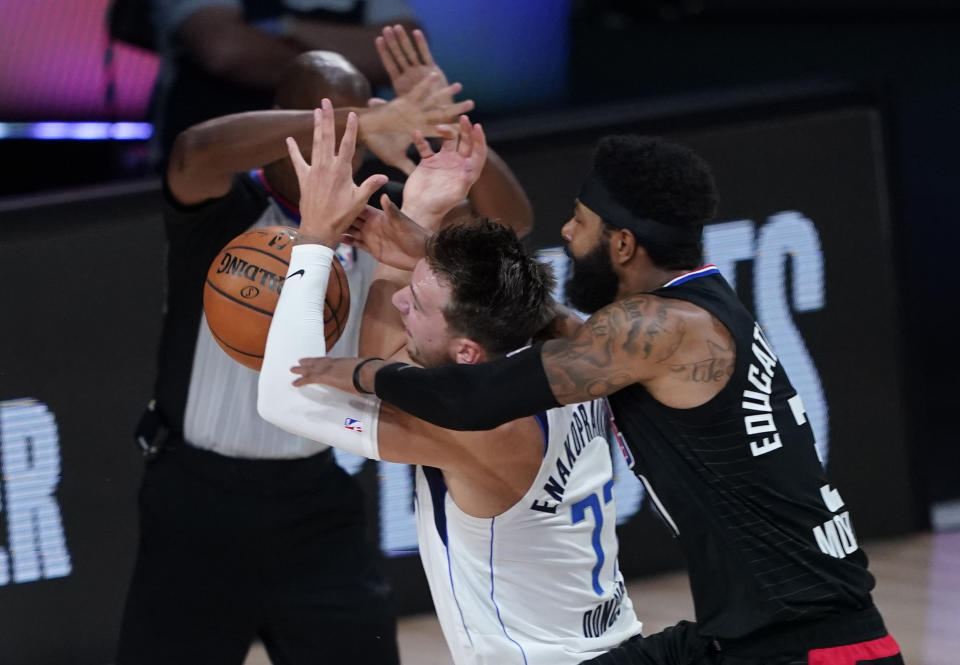 Dallas Mavericks' Luka Doncic (77) is fouled by Los Angeles Clippers' Marcus Morris Sr. during the first half of an NBA first round playoff game Sunday, Aug. 30, 2020, in Lake Buena Vista, Fla. (AP Photo/Ashley Landis)