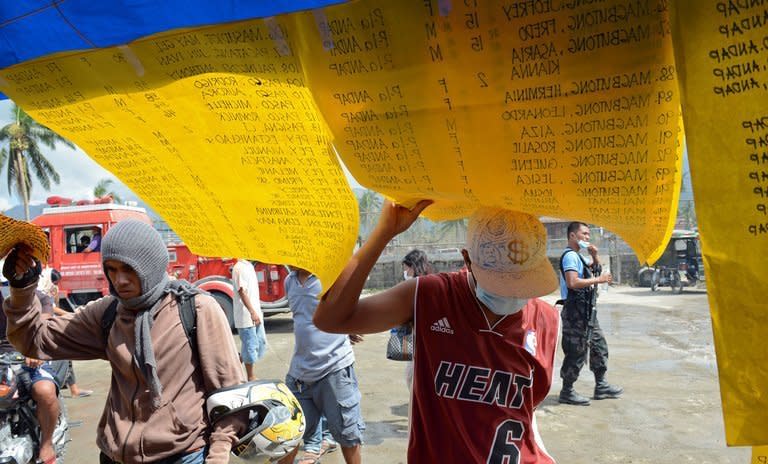 Residents look at lists displaying names of missing people in New Bataan, Philippines, on December 12, 2012. The death toll from a typhoon that devastated the southern Philippines earlier this month has topped 1,000 as hundreds more remain missing, the government said on Sunday